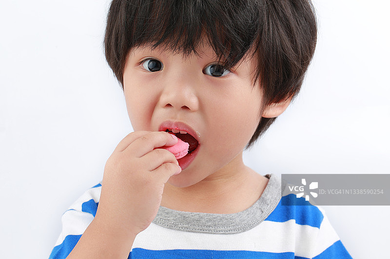 亚洲小男孩在白色背景下吃饼干图片素材