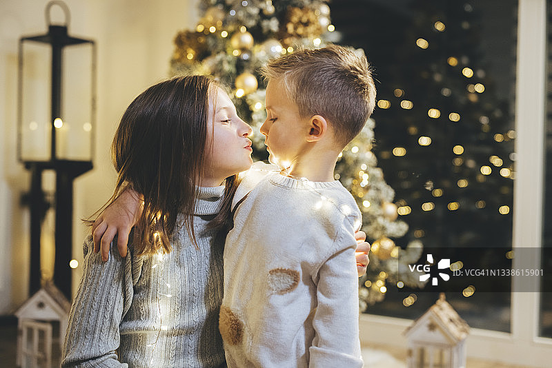 哥哥和妹妹在圣诞树前亲吻图片素材