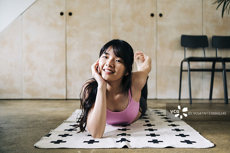 微笑的女人躺在毯子上锻炼图片素材
