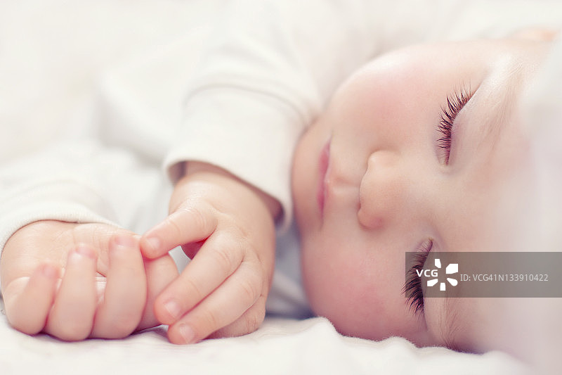 一个美丽的婴儿在白色上睡觉的特写图片素材
