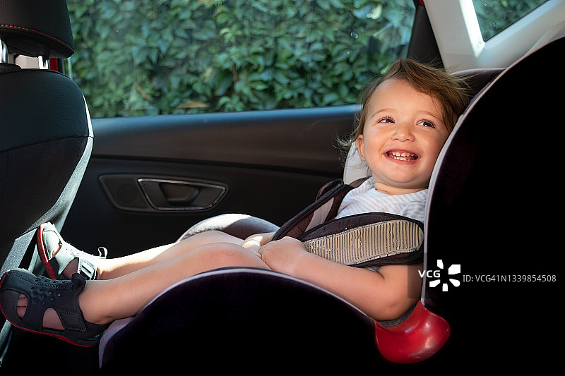 可爱的蹒跚学步的孩子在旅行时睡在汽车安全座椅上图片素材