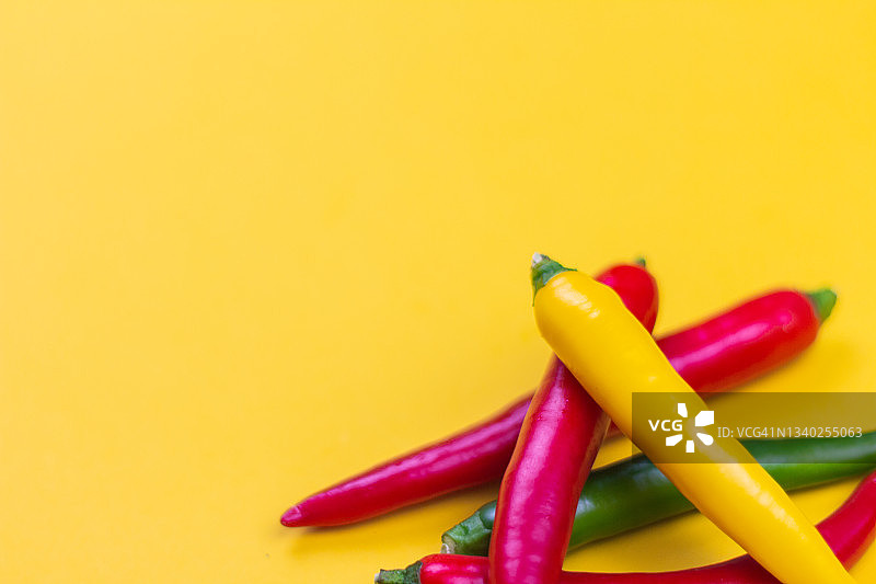 红色，黄色和绿色的辣椒在黄色的背景上。图片素材