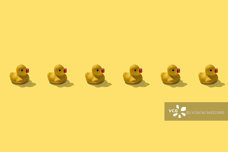 黄色背景上的六只橡皮鸭子排成一排图片素材