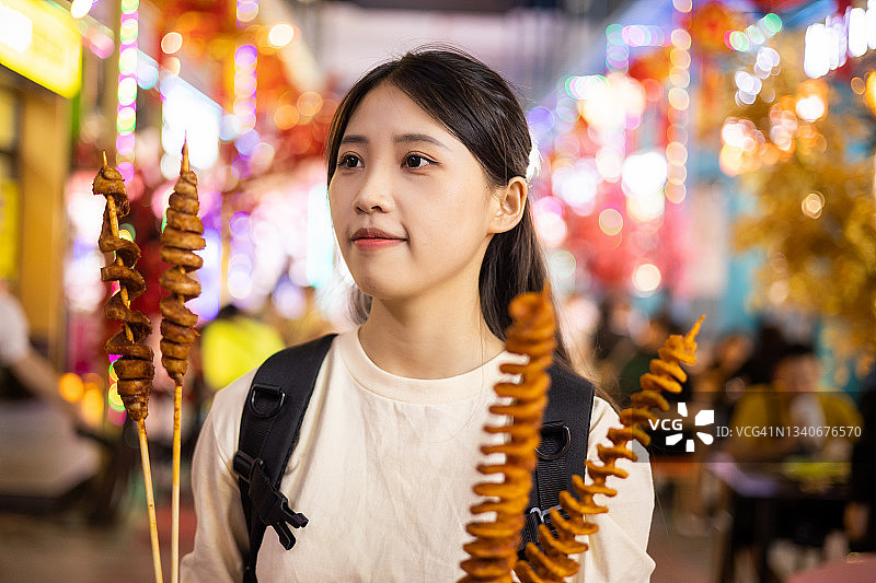年轻的亚洲妇女走在夜市街上图片素材
