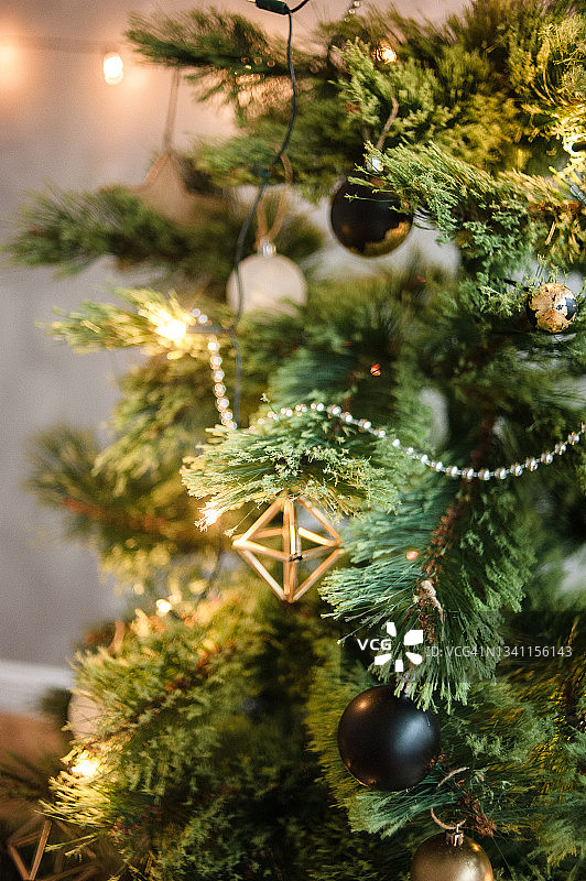 特写圣诞树上的灯，几何形状的细节，金色，白色和黑色的球。圣诞和新年的装饰主题与圣诞树在室内。图片素材