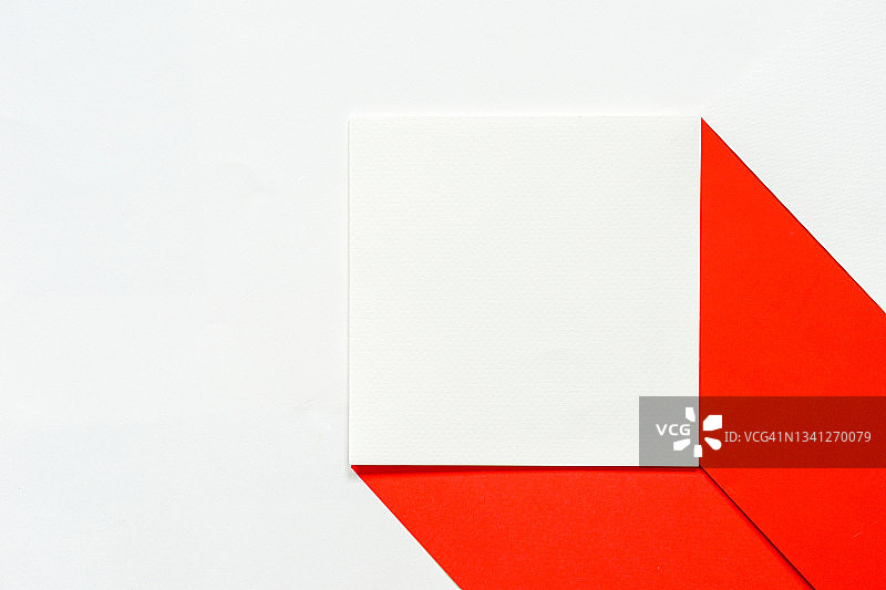 空白干净的白色正方形宣传册在红纸上对着白纸背景，身份模拟卡概念。图片素材