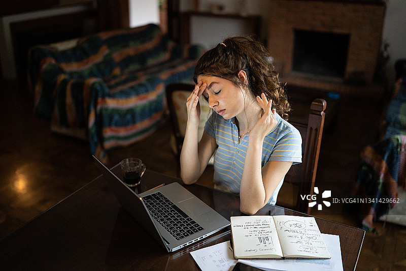 疲惫的年轻女子在家里用笔记本电脑图片素材