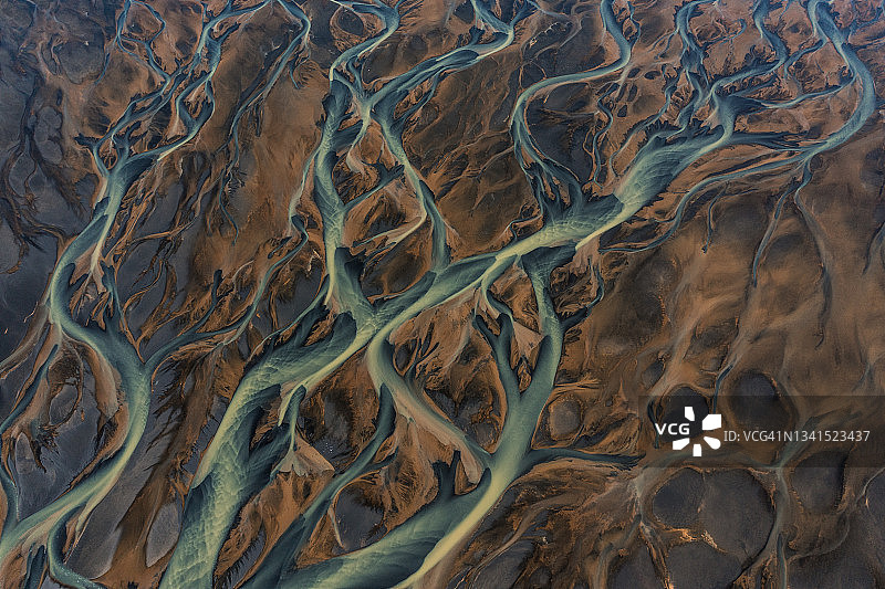 从高角度来看，一条辫状河流经冰岛的火山地貌图片素材