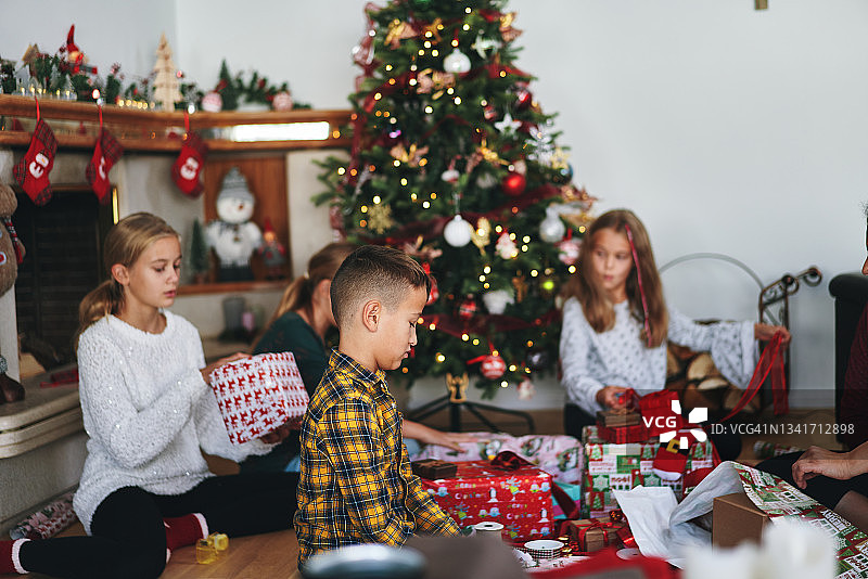 小孩子在圣诞树前包装和装饰圣诞礼物图片素材