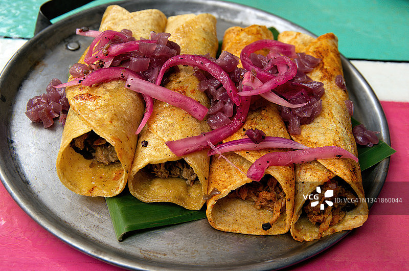墨西哥玉米卷和cochinita玉米卷，配以腌制和焦糖洋葱，放在大浅盘上图片素材