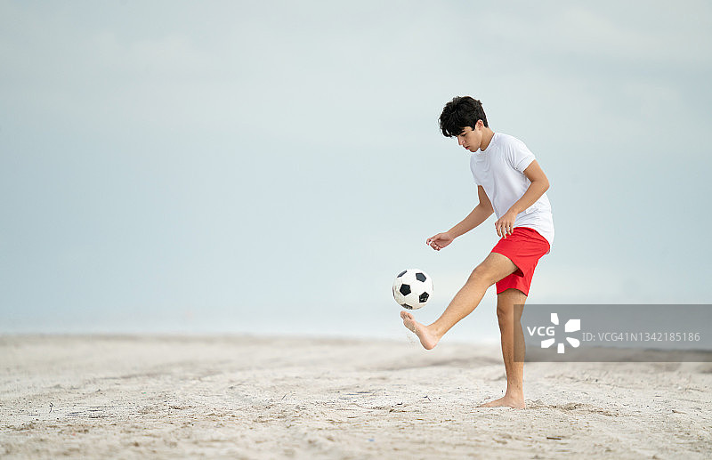 在迈阿密的海滩上，一名少年在玩足球杂耍图片素材