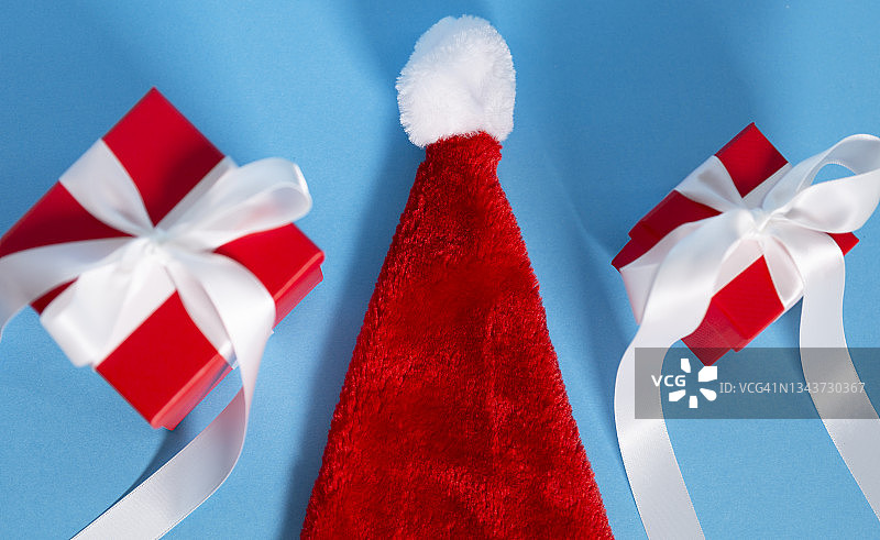 圣诞装饰圣诞帽和圣诞礼品盒以蓝色为背景图片素材