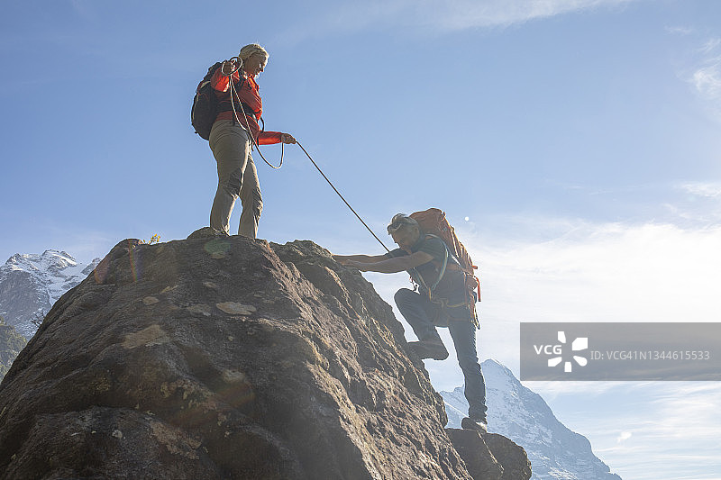 一对登山夫妇攀登瑞士阿尔卑斯山的岩壁图片素材