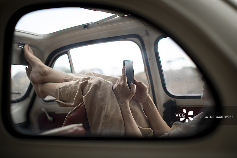 一个女人坐在一辆旧汽车里拿着手机图片素材