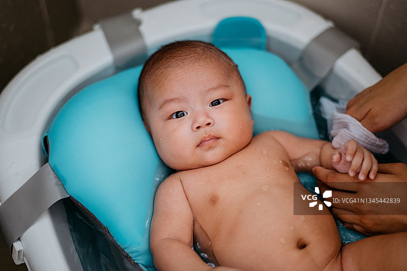 妈妈正在婴儿浴盆里给她的男婴洗澡图片素材