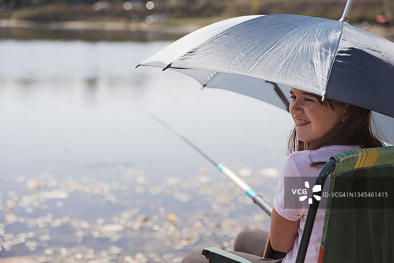 女孩微笑时用伞遮阳钓鱼时图片素材