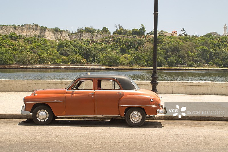 古巴哈瓦那，一辆老爷车在水边行驶图片素材