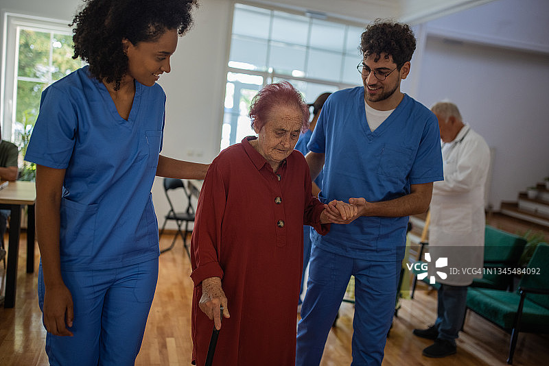 两名护理员在养老院协助老年妇女行走图片素材