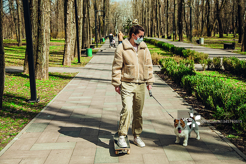 公园里有个年轻女人带着一只杰克罗素犬。图片素材