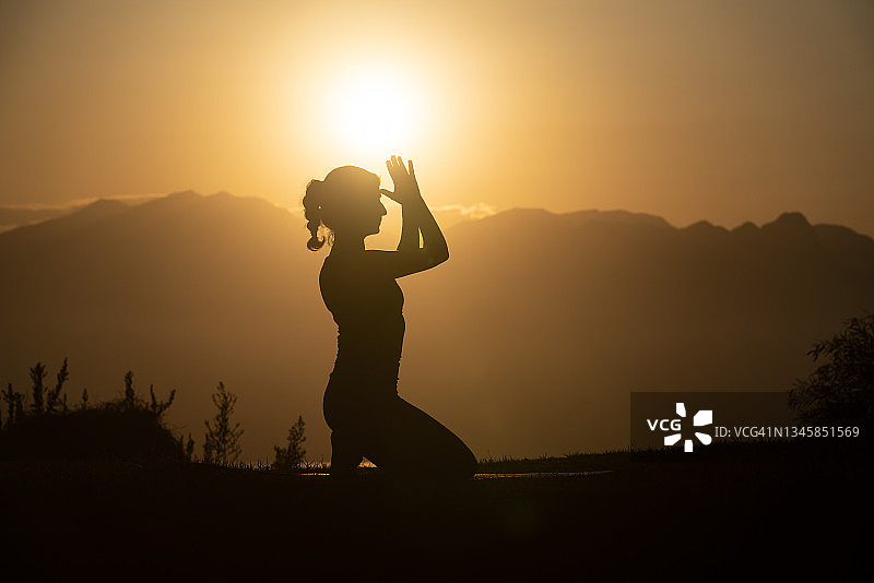 日落时练习瑜伽的成年妇女剪影照片图片素材