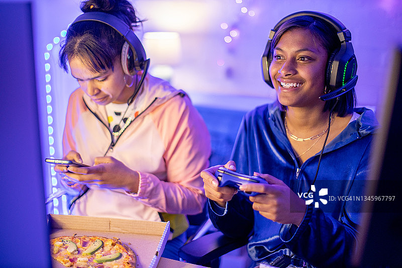 两个年轻的女性玩家在晚上玩游戏图片素材