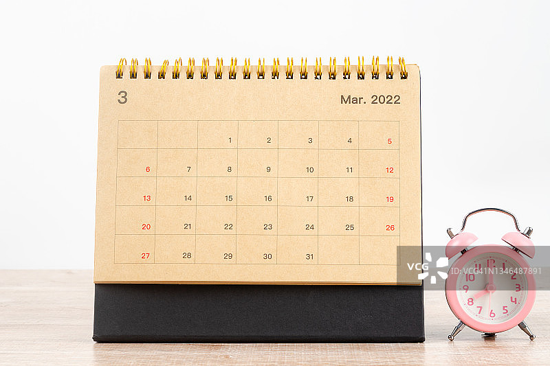 2022年3月月历台，家庭办公室木桌上的日历台和闹钟。图片素材