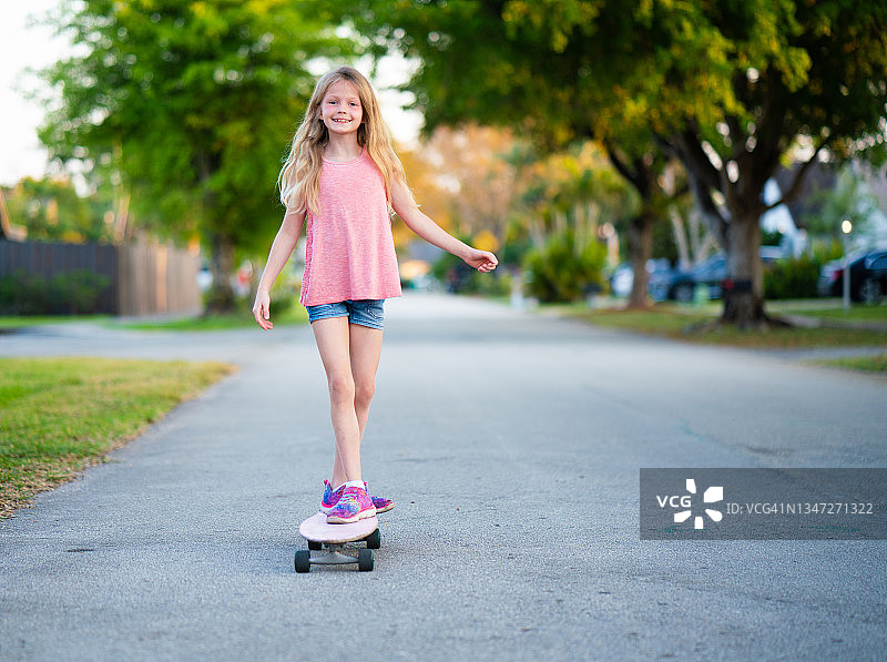 一个十几岁的女孩在附近玩滑板图片素材