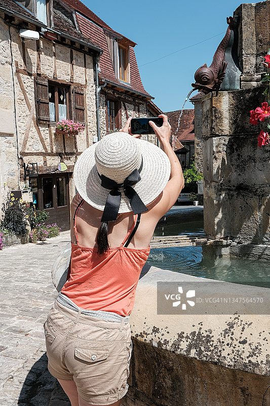 法国奥西坦尼，卡列纳克，Quercy，罗得，一个女人在拍摄喷泉的后视图图片素材