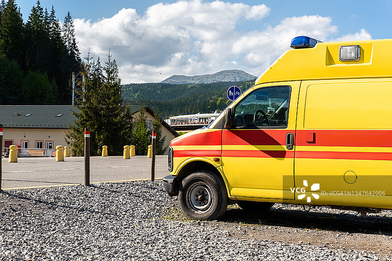 侧面的黄色救护车救援ems面包车停在乡村公路附近的高地山区度假区。护理人员急救帮助服务车辆对抗高山森林景观图片素材