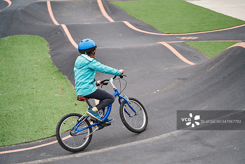 一个孩子在公园的混凝土泵轨道上骑自行车。图片素材