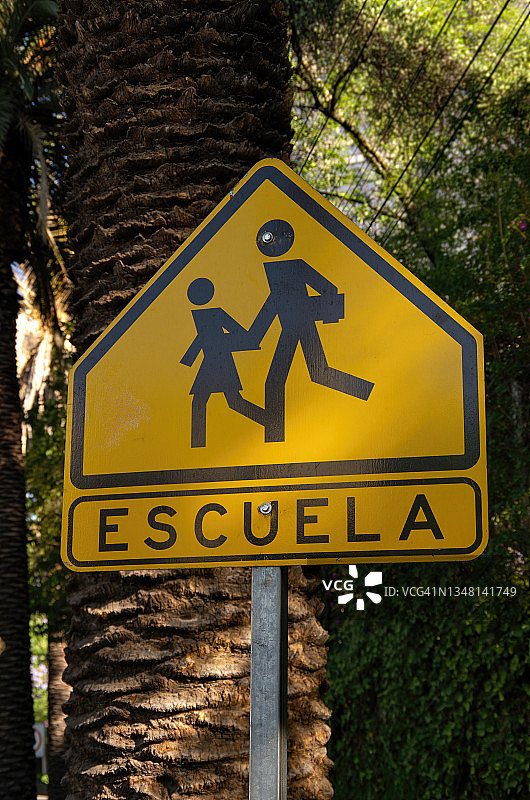 西班牙语道路警告标志，指示“Escuela”(学校)和学校儿童过境图片素材