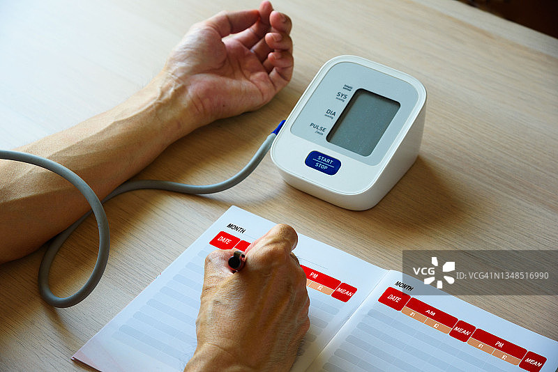 在家自行测量血压后写下血压数字。图片素材