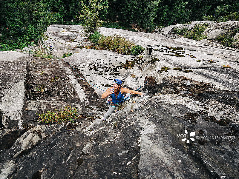 一名女攀岩者一边抽烟一边攀爬高大而引人注目的岩壁图片素材