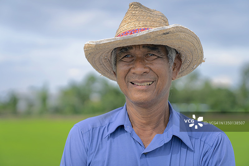 泰国农民高兴地微笑着看着稻田里的水稻图片素材