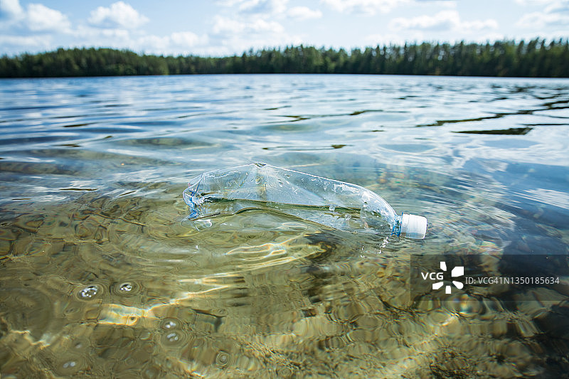 用过的塑料瓶漂浮在清澈的水中。图片素材