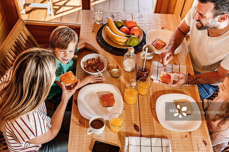 上图是一个年轻幸福的家庭在餐桌上享受他们的早餐。图片素材