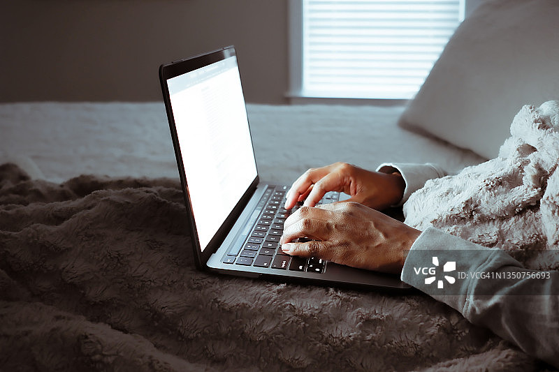 女人在床上用笔记本电脑工作图片素材