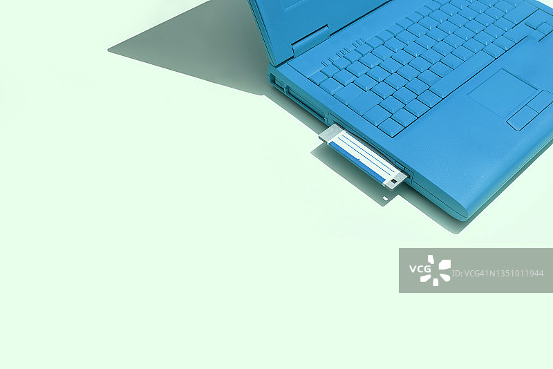 绿色背景和软盘上的蓝色笔记本电脑图片素材