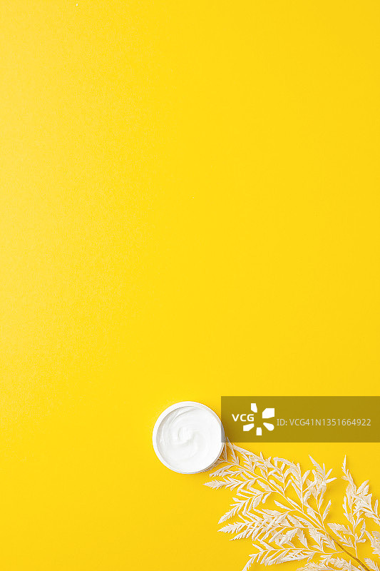 一罐黄色背景上有花的化妆品。平铺，复制空间图片素材