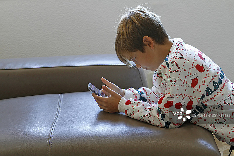 男孩在沙发上玩智能手机图片素材