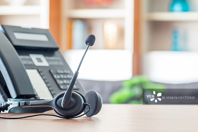 接近软焦点耳机与电话设备在办公室桌上为客户服务支持。VOIP耳机为客户服务支持(呼叫中心)的概念。图片素材