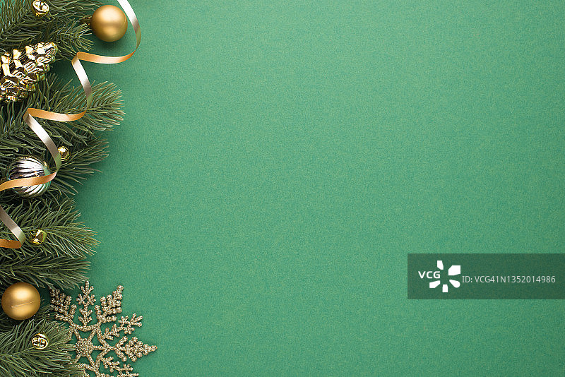 顶部视图照片的金和银圣诞树球玩具锥小铃铛，雪花和蛇在松树枝上孤立的绿色背景与空白图片素材