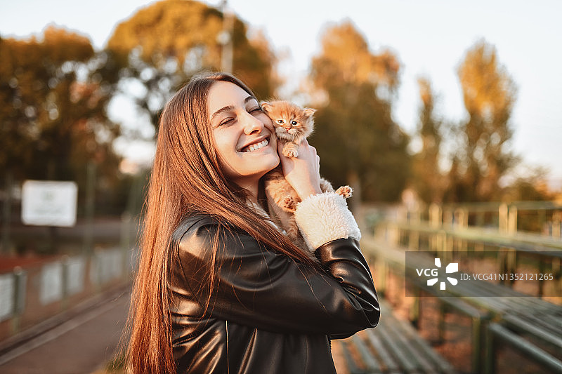 美丽的女性在夕阳下拥抱小猫表达的幸福图片素材