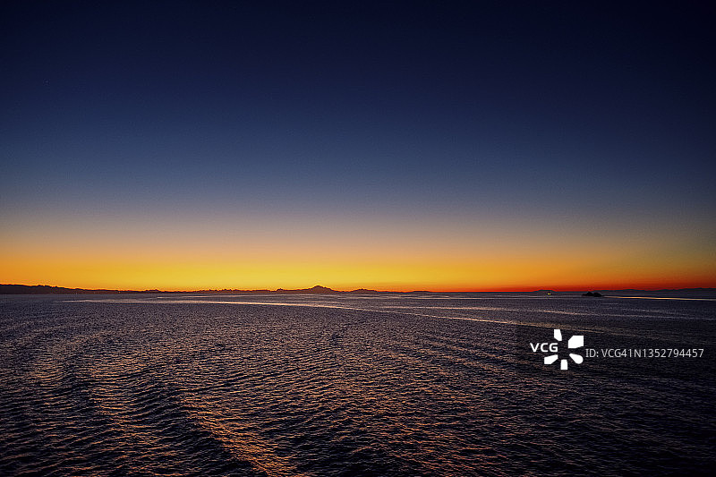 日出时，一艘船的尾流穿过太平洋，朝着不列颠哥伦比亚省的海岸线驶去图片素材