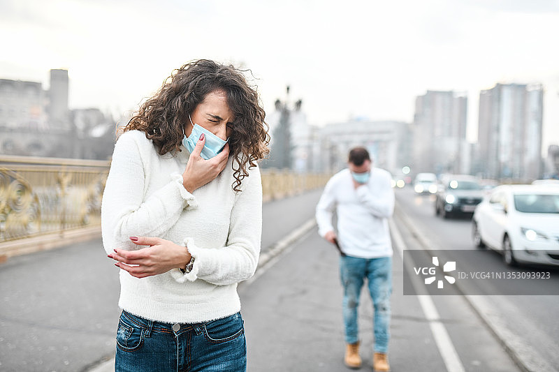 女性和男性在穿过城市时因空气污染而咳嗽图片素材