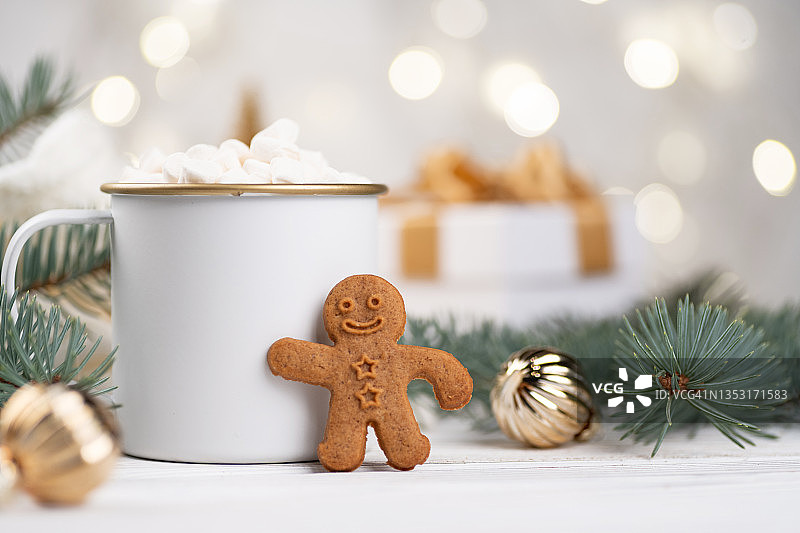 姜饼人的特写背景是一杯白色的可可，一棵圣诞树和散景灯图片素材