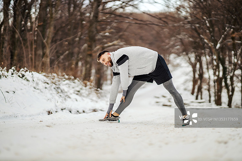 身体健康的运动员在雪天站在大自然中做伸展运动和热身运动。户外健身，冬季健身，健康的生活方式图片素材