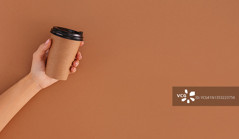 纸杯咖啡，米色背景上的标志在手中图片素材