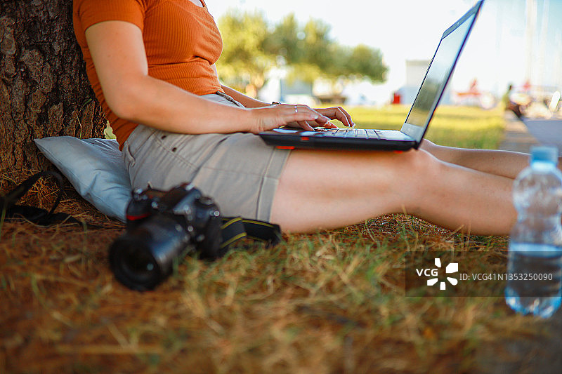 一个坐在草地上用笔记本电脑工作的女人图片素材