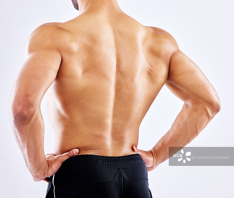 一个男人在摄影棚的白色背景下展示他的背部肌肉图片素材